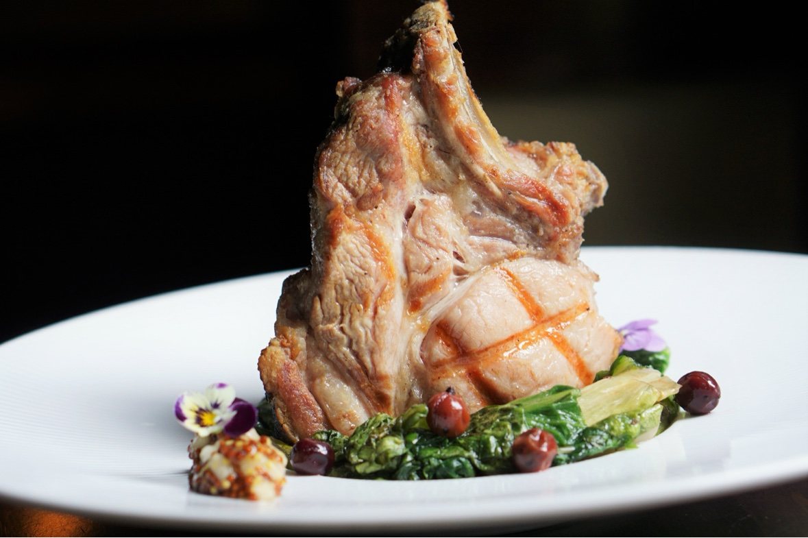 Bone in chop plated with greens and edible flowers