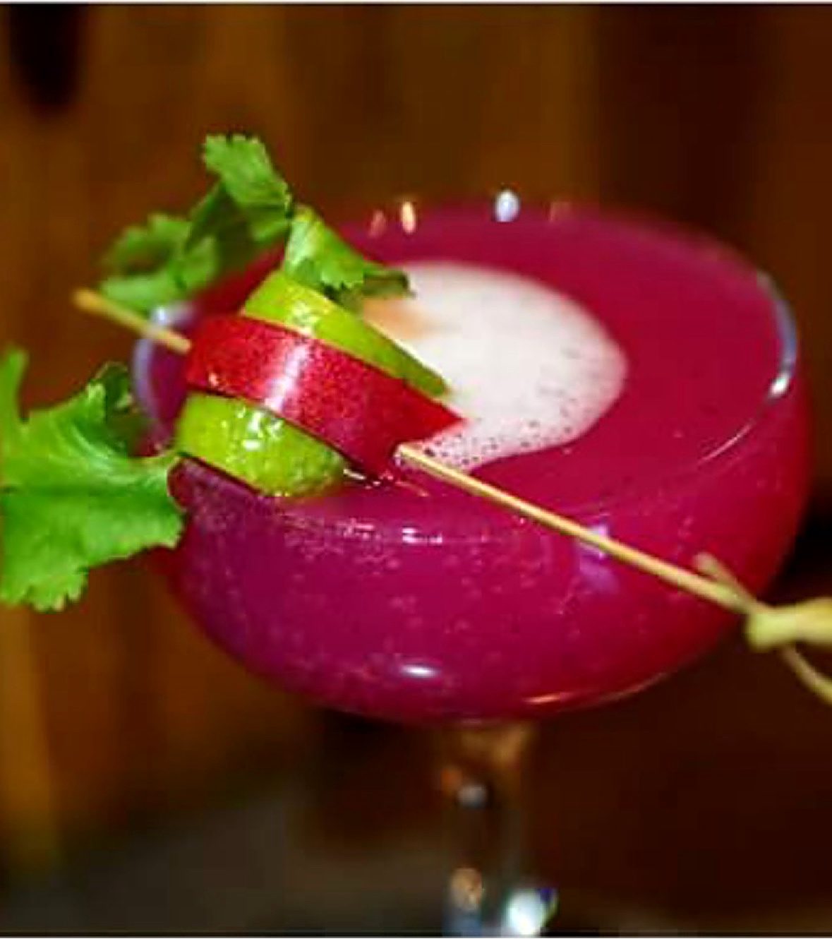 Bright magenta cocktail with lime and cilantro garnish