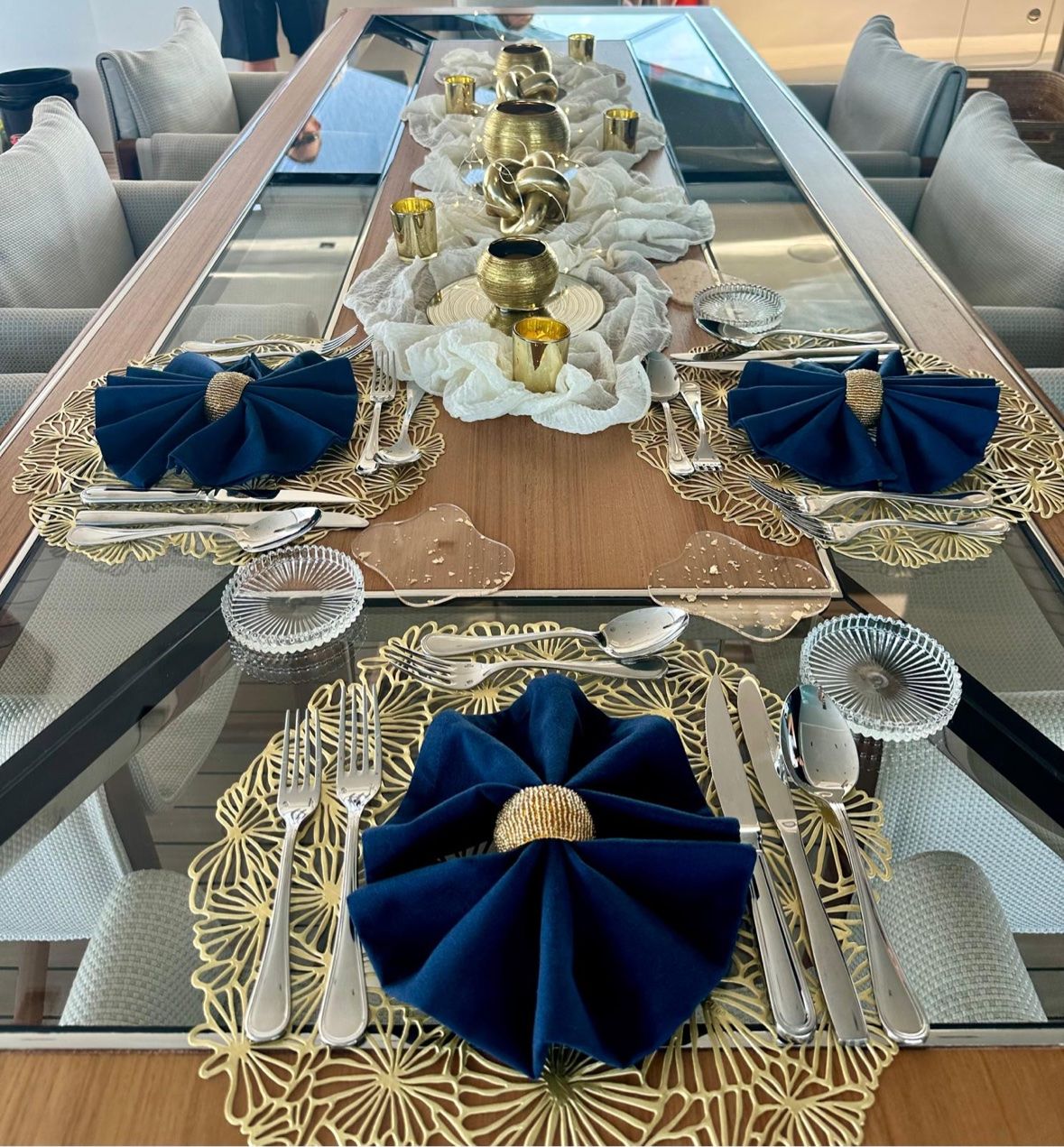 Navy and gold place settings with brass details on a glass table