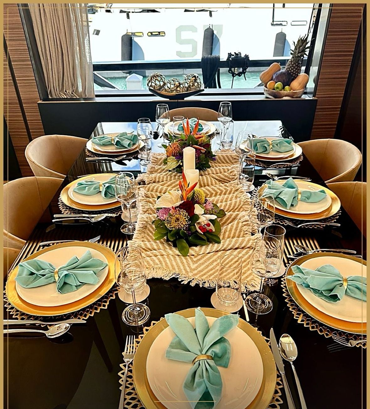 Table dressed with tropical florals, gold chargers and turquoise napkins